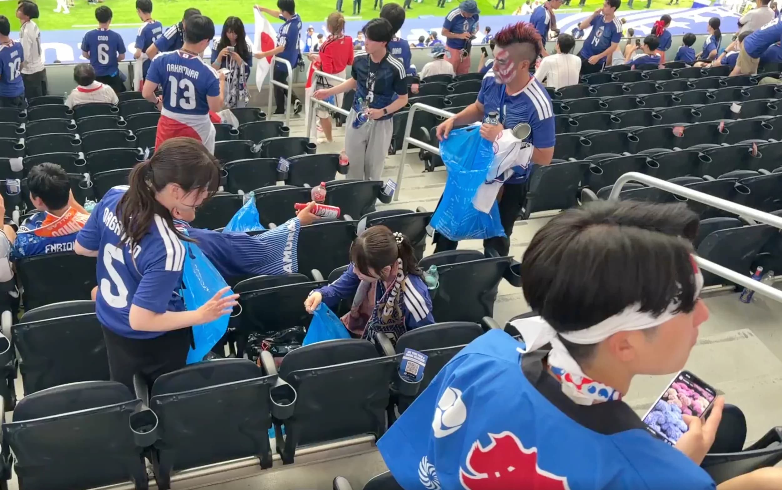 Suporter membersihkan sampah usai pertandingan antara Belanda melawan Jepang.