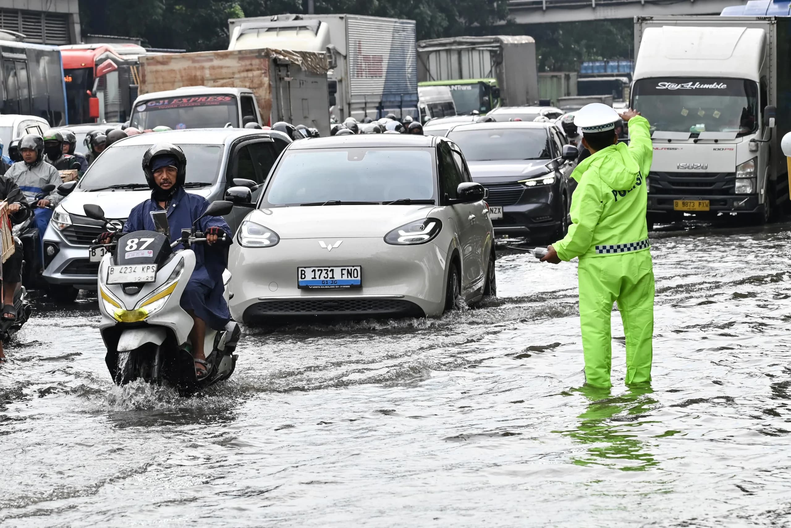 Petugas Kepolisian (kanan) mengatur lalu lintas kendaraan yang terjebak kemacetan saat melintasi genangan air di Cawang, Jakarta Petugas Kepolisian (kanan) mengatur lalu lintas kendaraan yang terjebak kemacetan saat melintasi genangan air di Cawang, Jakarta