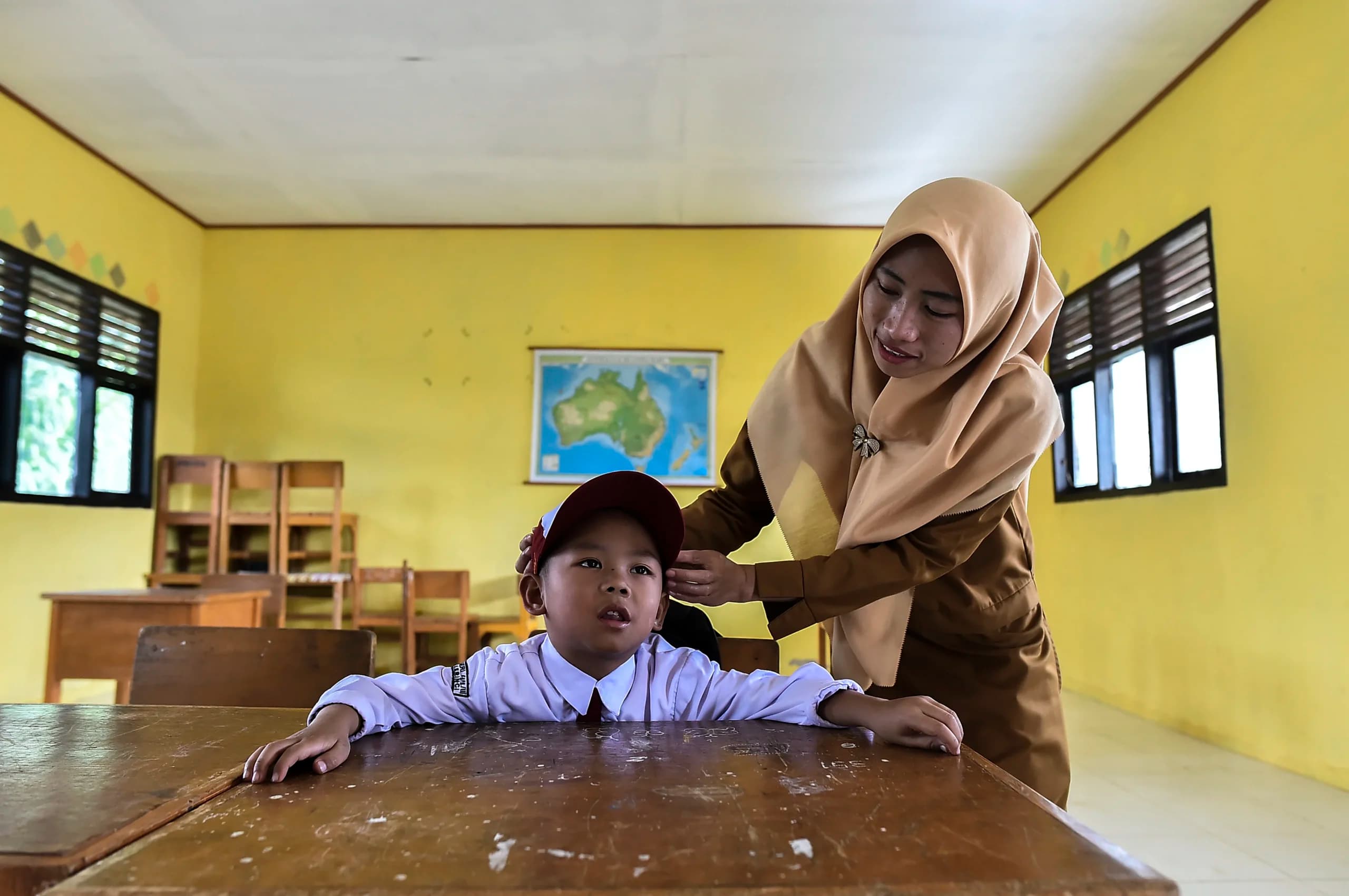 Guru merapikan topi siswa kelas 1 yang merupakan anak-anak transmigran saat kegiatan belajar mengajar di SDN 44/III Sungai Bermas, Kerinci, Jambi. (Sumber: Antara Foto/Wahdi Septiawan/agr) Guru merapikan topi siswa kelas 1 yang merupakan anak-anak transmigran saat kegiatan belajar mengajar di SDN 44/III Sungai Bermas, Kerinci, Jambi. (Sumber: Antara Foto/Wahdi Septiawan/agr)