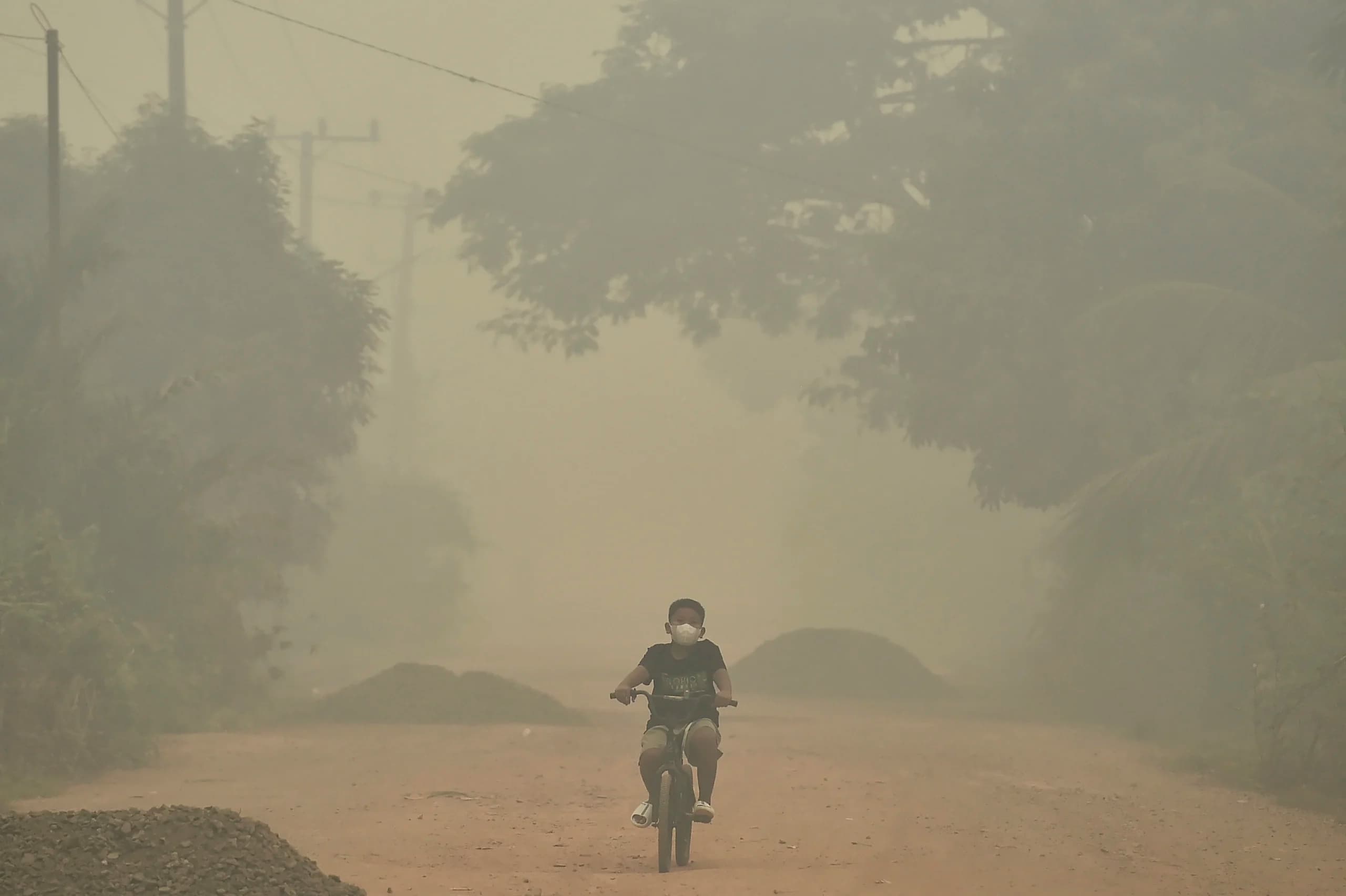 Seorang anak bersepeda di Jalan Orang Kayo Hitam yang diselimuti asap kebakaran hutan dan lahan (karhutla) di Kelurahan Simpang, Berbak, Tanjung Jabung Timur, Jambi Seorang anak bersepeda di Jalan Orang Kayo Hitam yang diselimuti asap kebakaran hutan dan lahan (karhutla) di Kelurahan Simpang, Berbak, Tanjung Jabung Timur, Jambi