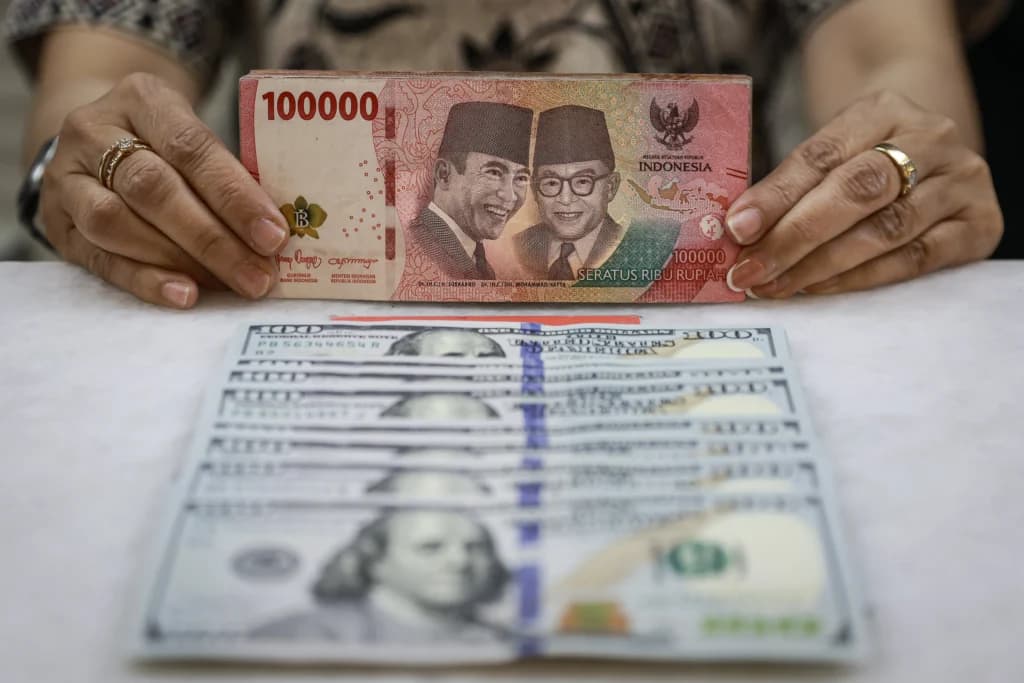 Karyawan menunjukkan uang pecahan rupiah dan dolar Amerika Serikat (AS) di gerai penukaran mata uang asing Ayu Masagung, Jakarta, Jumat (16/10/2026). Karyawan menunjukkan uang pecahan rupiah dan dolar Amerika Serikat (AS) di gerai penukaran mata uang asing Ayu Masagung, Jakarta, Jumat (16/10/2026).