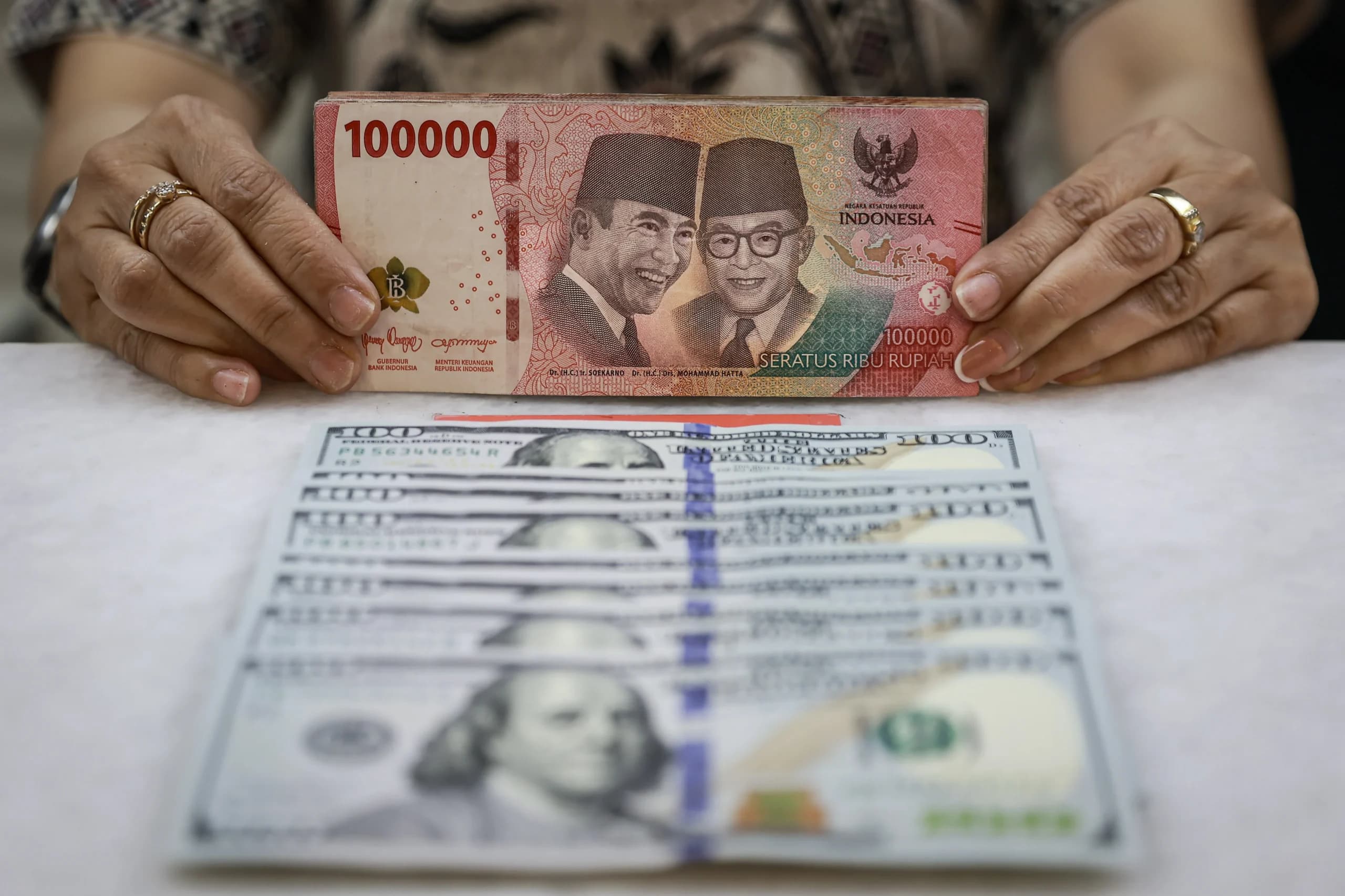 Karyawan menunjukkan uang pecahan rupiah dan dolar Amerika Serikat (AS) di gerai penukaran mata uang asing Ayu Masagung, Jakarta, Jumat (16/10/2026). Karyawan menunjukkan uang pecahan rupiah dan dolar Amerika Serikat (AS) di gerai penukaran mata uang asing Ayu Masagung, Jakarta, Jumat (16/10/2026).