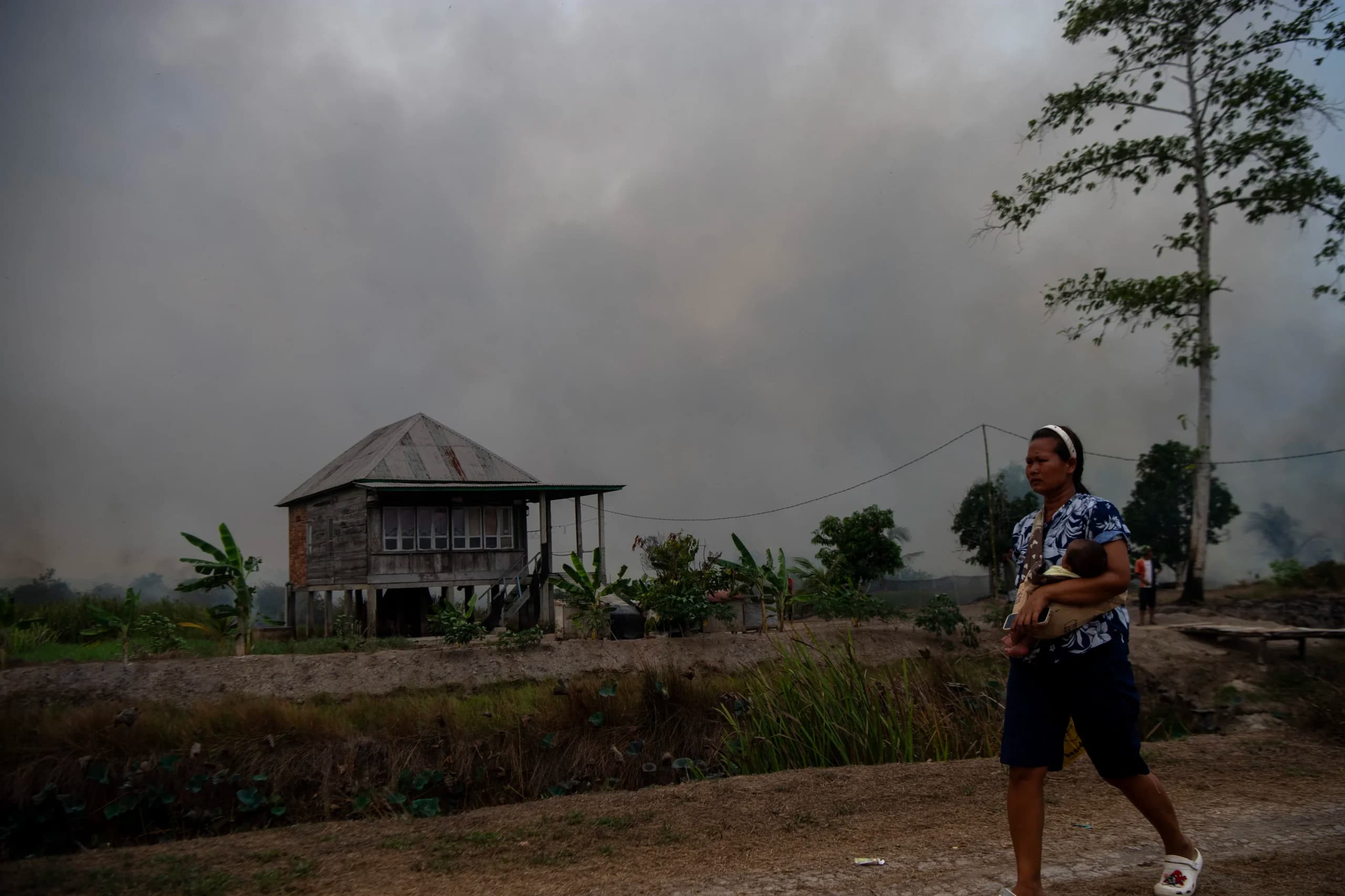 Warga berjalan menggendong anaknya saat terjadi kebakaran lahan di Desa Muara Baru, Pemulutan, Ogan Ilir (OI), Sumatera Selatan, Jumat (25/9/2026). Warga berjalan menggendong anaknya saat terjadi kebakaran lahan di Desa Muara Baru, Pemulutan, Ogan Ilir (OI), Sumatera Selatan, Jumat (25/9/2026).