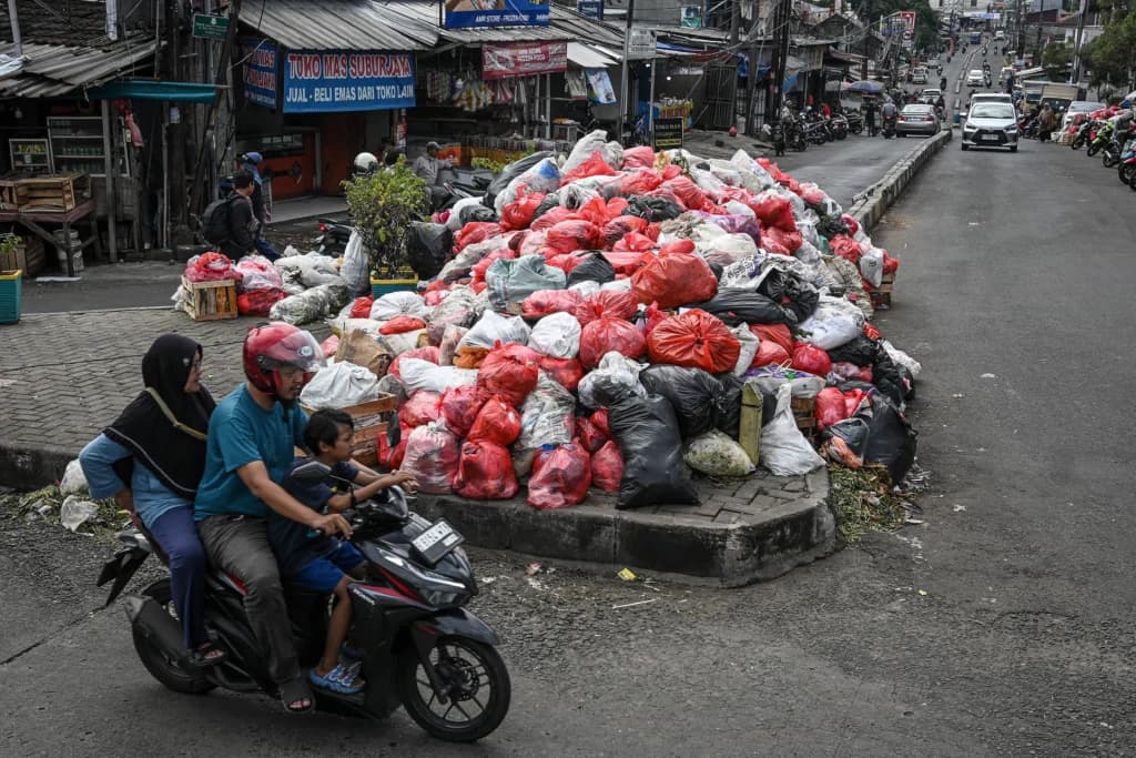 Pengendara sepeda motor melintas di dekat tumpukan sampah di Jalan Dewi Sartika, Ciputat, Tangerang Selatan, Banten, Sabtu (13/12/2025). Sumber: Antara Foto/Sulthony Hasanuddin/tom. Pengendara sepeda motor melintas di dekat tumpukan sampah di Jalan Dewi Sartika, Ciputat, Tangerang Selatan, Banten, Sabtu (13/12/2025). Sumber: Antara Foto/Sulthony Hasanuddin/tom.