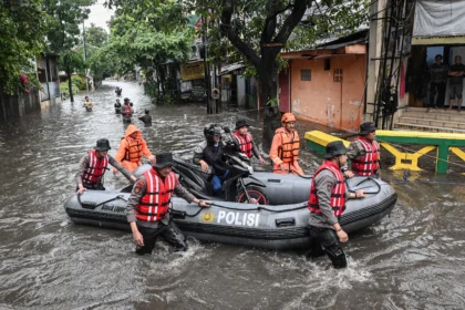 Personel polisi membantu warga mengevakuasi sepeda motor saat banjir di Kompleks Polri Pondok Karya, Mampang Prapatan, Jakarta, Selasa (18/11/2025). Badan Penanggulangan Bencana Daerah DKI Jakarta mencatat terdapat 13 RT di Jakarta Selatan yang tergenang banjir dengan ketinggian 30-80 centimeter akibat luapan air kali sebagai dampak dari tingginya intensitas hujan.
