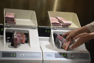 Petugas menghitung uang rupiah di Kantor Cabang BNI Pasar Baru