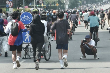 Seorang fotografer memotret warga yang berolahraga saat Hari Bebas Kendaraan Bermotor (HBKB) di kawasan Bundaran HI