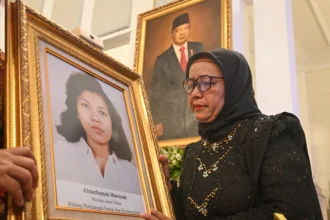 Adik aktivis buruh Marsinah, Wijiyati memandang foto kakaknya usai mengikuti prosesi upacara pemberian gelar pahlawan kepada Marsinah