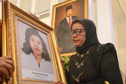 Adik aktivis buruh Marsinah, Wijiyati memandang foto kakaknya usai mengikuti prosesi upacara pemberian gelar pahlawan kepada Marsinah