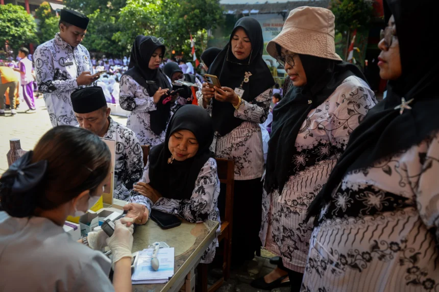 Tenaga kesehatan memeriksa kadar gula darah guru saat peringatan Hari Guru Nasional