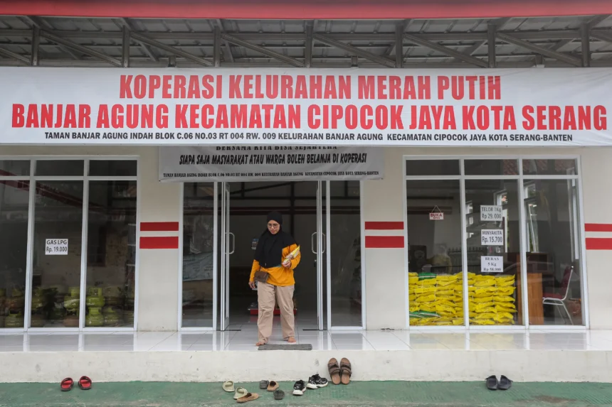 Warga membawa minyak goreng yang dibeli di Koperasi Kelurahan Merah Putih