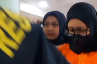 Founder Wo, Ayu Puspita Dewi memakai baju tahanan oranye memakai kerudung hitam di Polda Metro Jaya