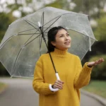 Seorang wanita memakai payung saat hujan