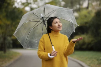 Seorang wanita memakai payung saat hujan