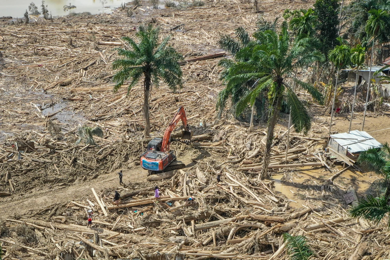 Petugas mengoperasikan eskavator untuk membersihkan jalan akses antardesa dari batang-batang kayu gelondongan pascabanjir bandang di Desa Tanjung Karang, Karang Baru, Kabupaten Aceh Tamiang, Aceh