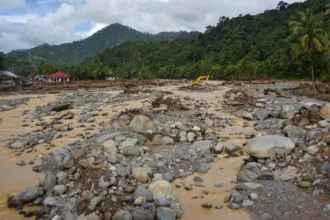 Operator mengoperasikan alat berat untuk membersihkan lokasi dari material banjir bandang di aliran Sungai Batang Kuranji, Batu Busuk, Padang, Sumatera Barat