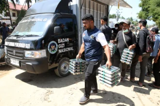 Petugas Satuan Pelayanan Pemenuhan Gizi (SPPG) Badan Gizi Nasional mengantar makanan untuk pengungsi bencana banjir luapan Sungai Meureudu di dapur umum Desa Manyang Cut, Pidie Jaya, Aceh