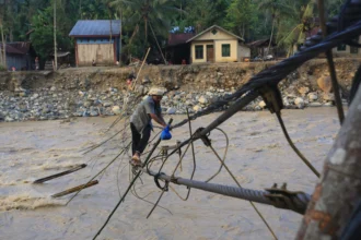 Sejumlah warga melintasi jembatan alternatif yang menghubungkan Desa Blang Meurandeh dan Desa Blang Puuk Beutong Ateuh Banggalang, Nagan Raya, Aceh, Minggu (30/11/2025).
