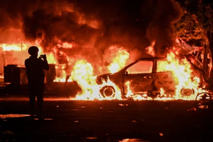 Warga mengambil gambar mobil yang dibakar massa saat kericuhan di kawasan Kalibata, Jakarta, Kamis (11/12/2025).