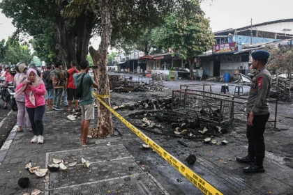 Polisi berjaga di area kios-kios yang terbakar pascakericuhan di kawasan Kalibata, Jakarta, Jumat (12/12/2025).