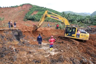 Petugas menggunakan alat berat melakukan pencarian korban longsor