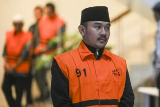 Bupati Bekasi Ade Kuswara Kunang berjalan mengenakan rompi tahanan usai terjaring operasi tangkap tangan (OTT) di Gedung Merah Putih KPK, Jakarta, Sabtu (20/12/2025).