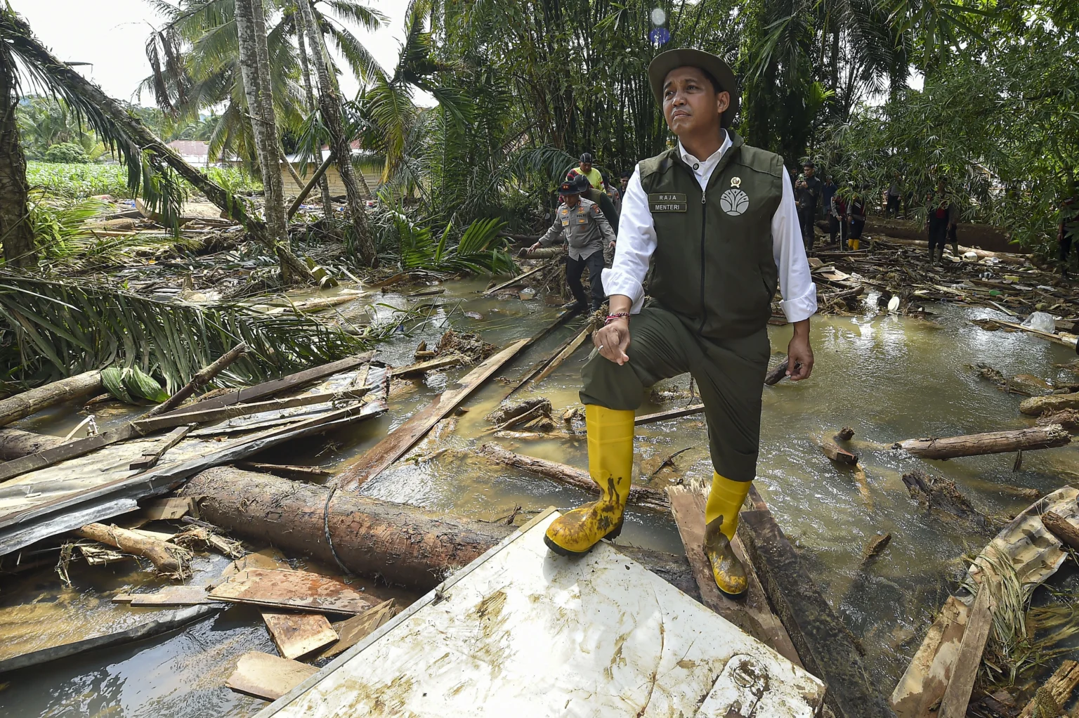 Menteri Kehutanan Raja Juli Antoni berdiri di atas tumpukan kayu yang hanyut saat meninjau proses pencarian korban banjir bandang di Pasak Kayu, Nagari Salareh Aia, Palembayan, Agam, Sumatera Barat, Minggu (30/11/2025).