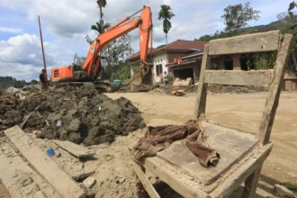 Petugas mengoperasikan alat berat untuk membersihkan material lumpur pascabencana di halaman rumah warga di Desa Rumah Bundar, Ketambe, Aceh Tenggara, Aceh