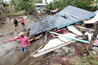 Warga melintas di dekat rumah yang hancur akibat bencana banjir bandang di Desa Alue Kuta, Kecamatan Jangka, Bireuen, Aceh