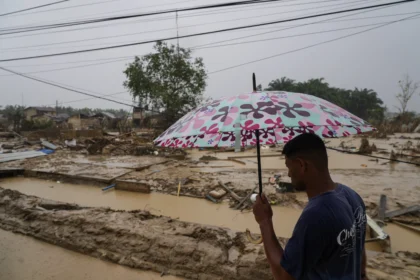 Warga berjalan di desa yang luluh lantak pascabanjir di Desa Bundar, Karang Baru, Kabupaten Aceh Tamiang, Aceh