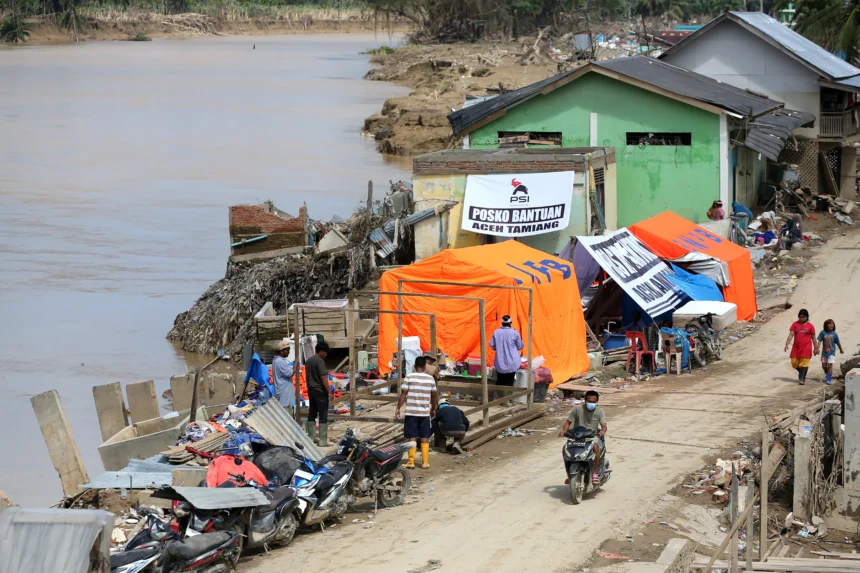 Warga korban bencana hidrometeorologi membangun tenda bantuan di pinggir Sungai Tamiang, Aceh Tamiang, Aceh