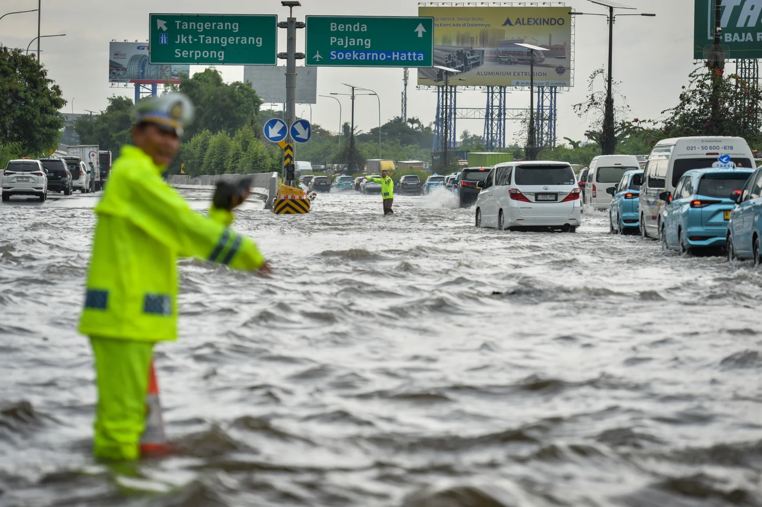 Polisi mengatur lalu lintas kendaraan saat banjir di Jalan Tol Sedyatmo, Kota Tangerang, Banten