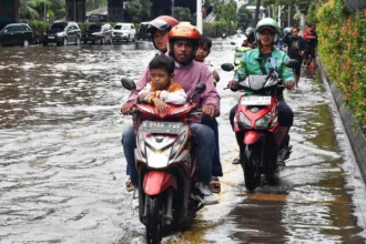 Pengendara sepeda motor melaju di atas trotoar saat banjir menggenangi Jalan Ahmad Yani, Cempaka Putih, Jakarta