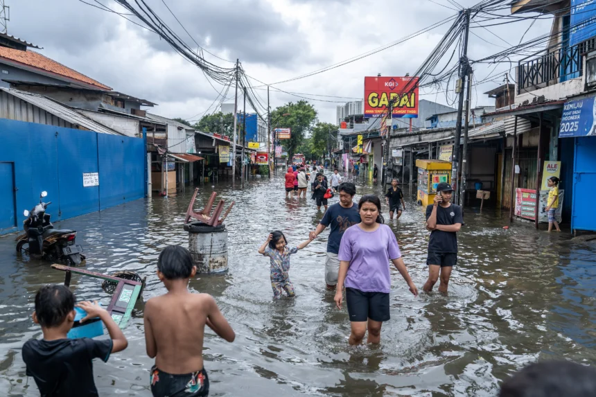 Warga melintasi banjir yang merendam perkampungan di Rawa Buaya, Cengkareng, Jakarta