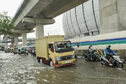 Pengendara melintasi banjir rob di Jalan R.E Martadinata, Tanjung Priok, Jakarta Utara