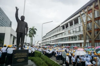Buruh dan karyawan keluar pabrik melintas di samping patung pendiri Sritex HM. Lukminto di Pabrik Sri Rejeki Isman Tbk (Sritex) di Sukoharjo, Jawa Tengah, Jumat (28/2/2025).