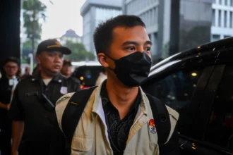 Petugas KPK berjalan menuju mobil usai melakukan penggeledahan di Kantor Direktorat Jenderal Pajak Kementerian Keuangan (DJP Kemenkeu), Jakarta, Selasa (13/1/2026).