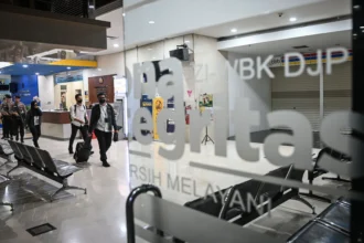 Petugas KPK membawa barang bukti usai melakukan penggeledahan di Kantor Pelayanan Pajak Madya Jakarta Utara, Jakarta, Senin (12/1/2026).