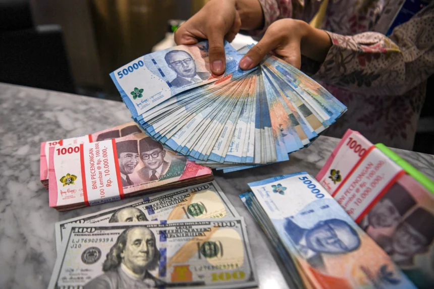 Petugas menunjukkan pecahan mata uang Rupiah dan Dolar Amerika Serikat (AS) di Kantor Cabang BNI Pasar Baru, Jakarta
