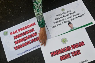 Peserta aksi dari Perkumpulan Guru Madrasah (PGM) Indonesia menata poster pada aksi damai di depan Gedung DPR/MPR, Jakarta. (Sumber: Antara Foto/Fakhri Hermansyah/rwa)