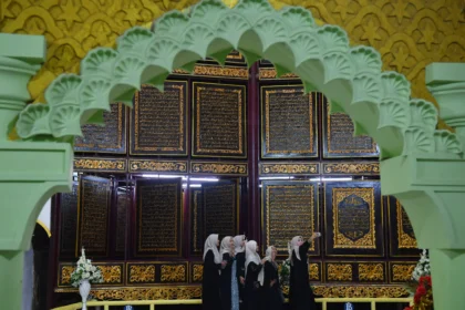 Wisatawan berswafoto dengan latar belakang ukiran ayat-ayat Al Quran yang dipajang di Al Quran Al Akbar, Gandus, Palembang, Sumatera Selatan