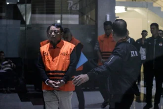 Ketua Pengadilan Negeri Depok I Wayan Eka Mariarta (kiri) berjalan menuju mobil tahanan usai menjalani pemeriksaan setelah terjerat Operasi Tangkap Tangan (OTT) di Gedung Merah Putih KPK, Jakarta, Sabtu (7/2/2026) dinihari.