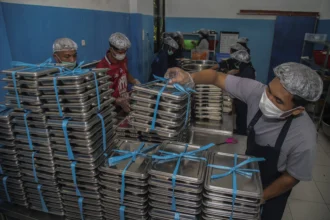 Petugas menyusun ompreng berisi Makan Bergizi Gratis (MBG) di dapur SPPG Tubo Ternate, Maluku Utara