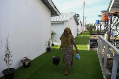 Warga berjalan menuju kamar mandi hunian sementara (Huntara) Danantara di Karang Baru Kabupaten Aceh Tamiang, Aceh