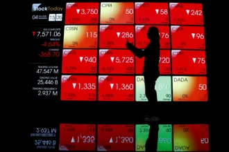 Pengunjung melintas di depan layar yang menampilkan pergerakan Indeks Harga Saham Gabungan (IHSG) di Bursa Efek Indonesia, Jakarta.