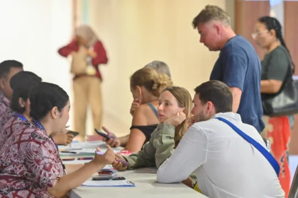 Petugas memberikan informasi kepada calon penumpang pesawat di area Terminal Internasional Bandara Internasional I Gusti Ngurah Rai, Badung, Bali