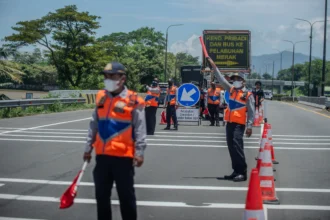 Petugas melakukan pengalihan arus truk di simpang susun pintu keluar tol Cilegon Timur, Kota Cilegon, Banten