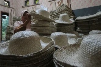 Perajin merapikan topi anyaman daun pandan yang belum terjual di Desa Medong, Mekarjaya, Pandeglang, Banten, Senin (2/3/2026). Sebanyak 157 perajin topi anyaman daun pandan dari dua kecamatan di Pandeglang terancam kehilangan mata pencaharian setelah kerja sama ekspor dengan perusahaan mitra dihentikan sejak Februari 2026, sementara pasar lokal belum mampu menyerap produk dalam jumlah besar seperti permintaan pasar ekspor. (ANTARA FOTO/Angga Budhiyanto/nz)