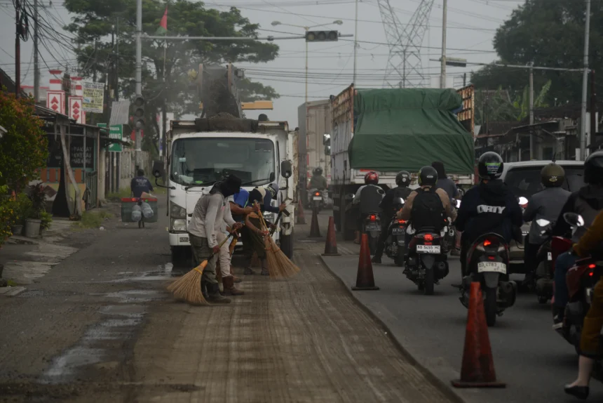 Pekerja menyapu serpihan aspal saat perbaikan Jalan Nasional Jogja-Solo di Klaten, Jawa Tengah