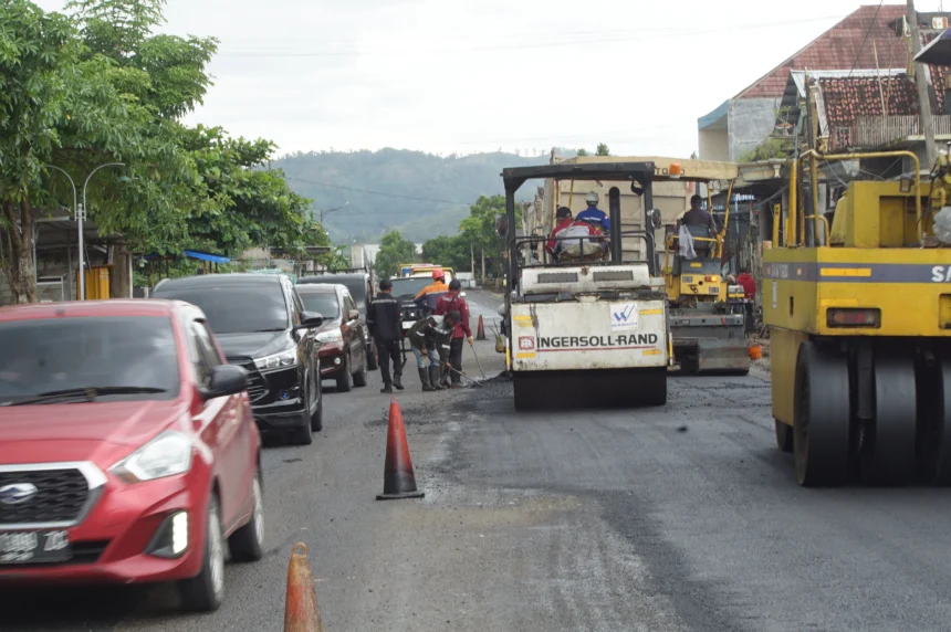 Pekerja mengoperasikan alat berat untuk meratakan dan memadatkan aspal hotmix saat pengerjaan proyek pelebaran jalan di ruas Campurdarat, Tulungagung, Jawa Timur